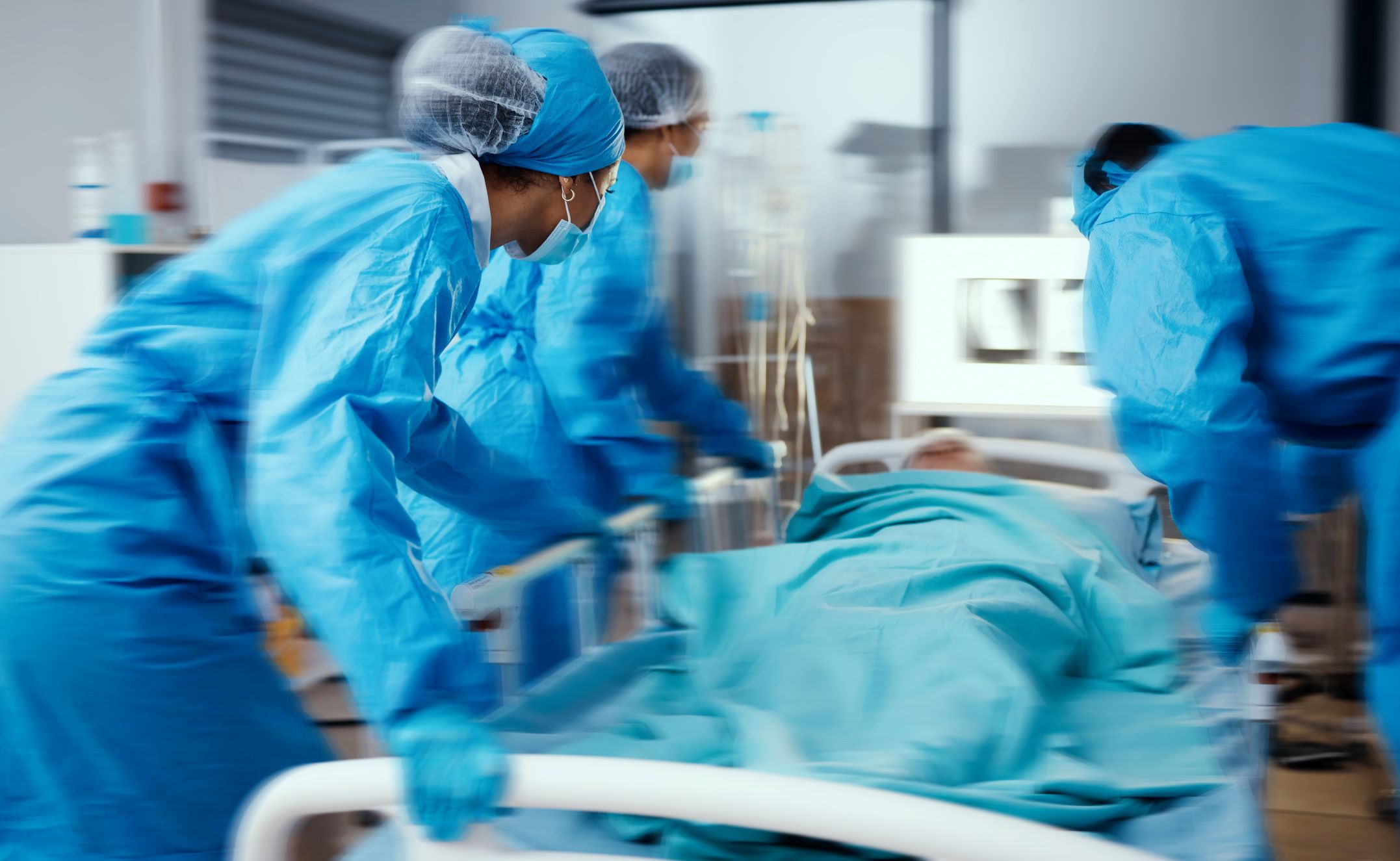 Medical personnel push hospital bed with patient who has chronic health condition during an emergency.